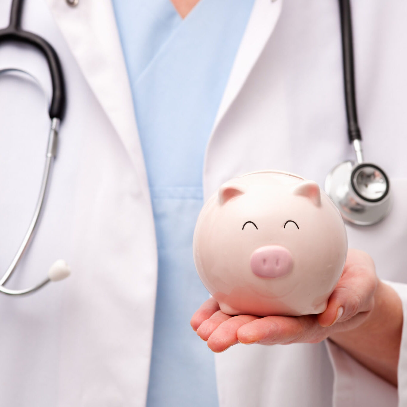 Female doctor with stethoscope holding piggy bank